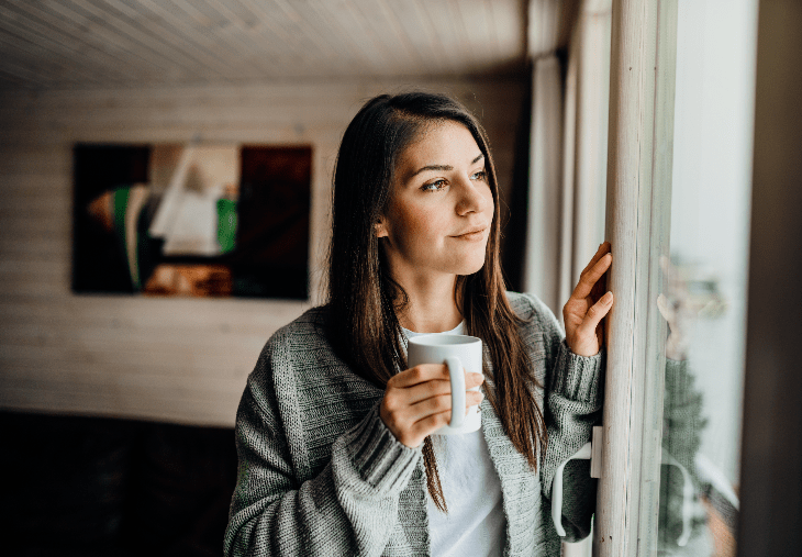 woman looking contemplative by window