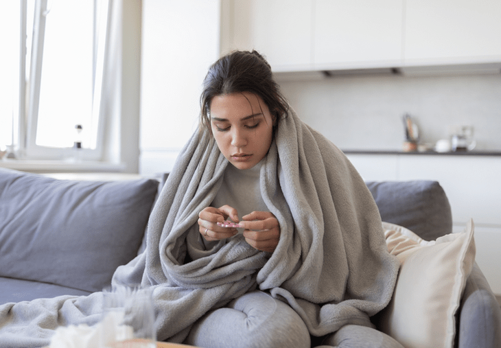 Woman taking medication on couch